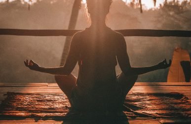 woman doing yoga meditation on brown parquet flooring